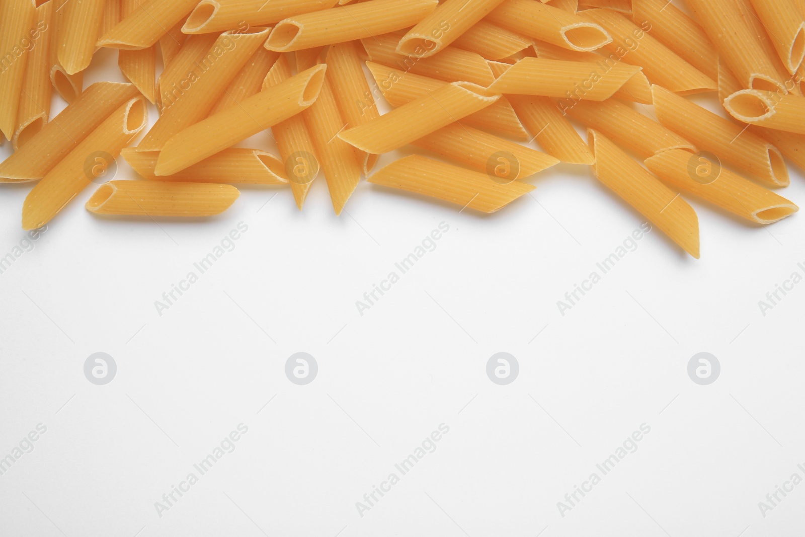 Photo of Raw penne pasta on white background, top view. Space for text