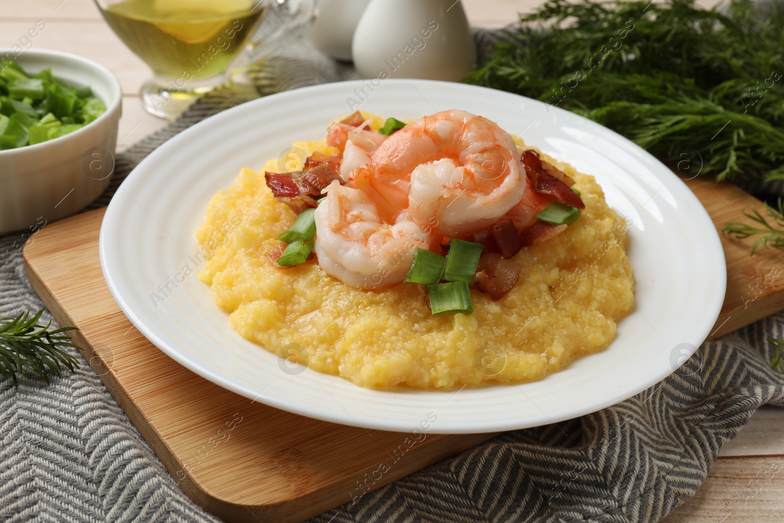 Photo of Plate with fresh tasty shrimps, bacon, grits and green onion on wooden table