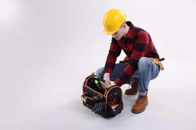 Photo of Professional repairman with tool box on light grey background. Space for text