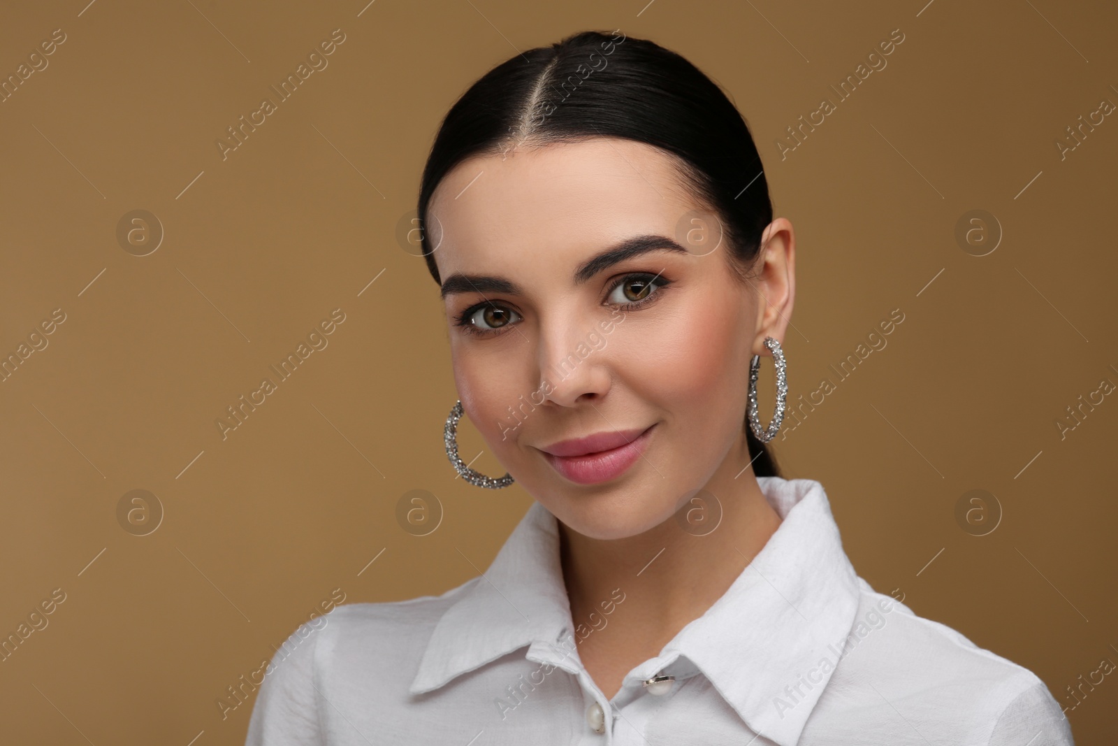 Photo of Beautiful young woman with elegant earrings on beige background