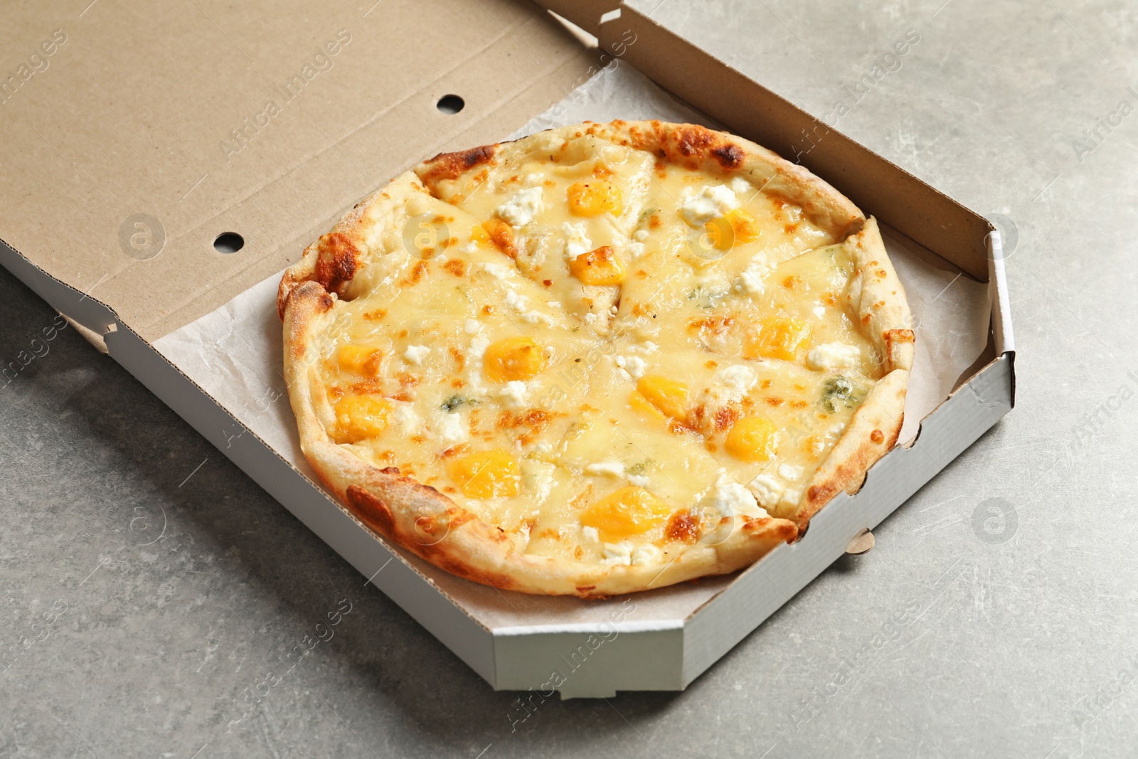 Photo of Carton box with cheese pizza on grey table. Food delivery service