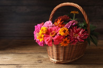 Beautiful wild flowers in wicker basket on wooden table. Space for text