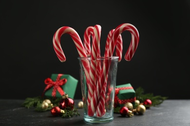Photo of Candy canes and Christmas decor on black table against dark background