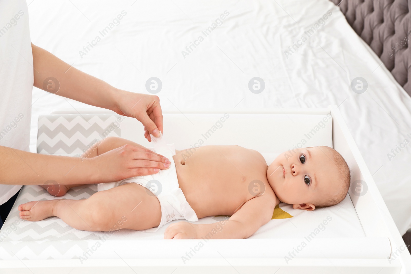 Photo of Mother changing her baby's diaper on table indoors