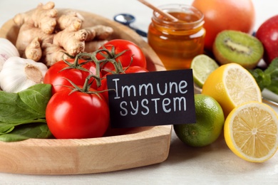 Photo of Card with phrase Immune System and fresh products on light table, closeup