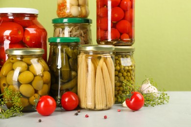 Photo of Jars of pickled vegetables and ingredients on light table