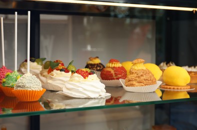 Showcase with different tasty desserts in store, closeup