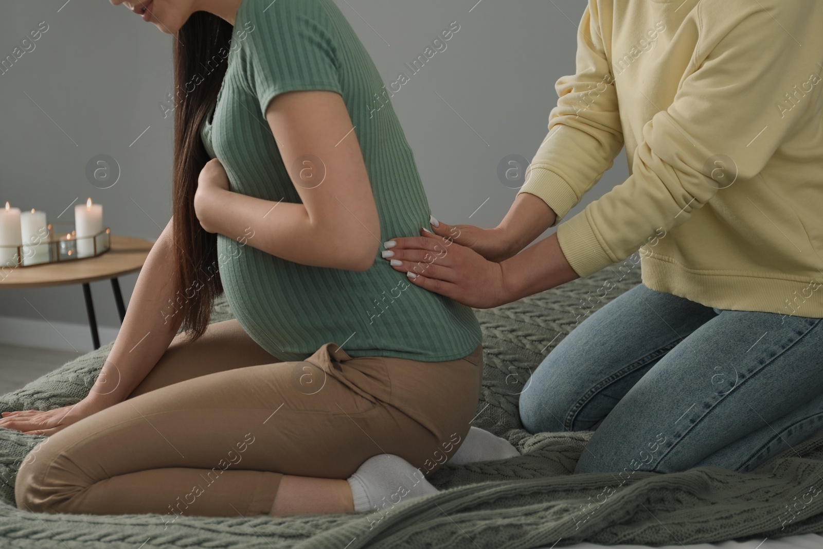 Photo of Doula massaging pregnant woman indoors, closeup. Preparation for child birth