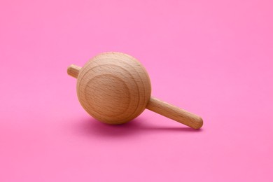 One wooden spinning top on pink background. Toy whirligig