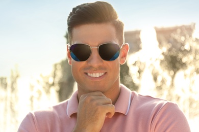 Handsome man wearing stylish sunglasses on city street, closeup