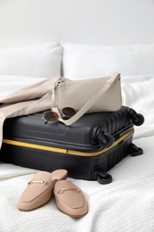 Photo of Suitcase packed for trip, shoes, jacket and fashionable accessories on bed in room