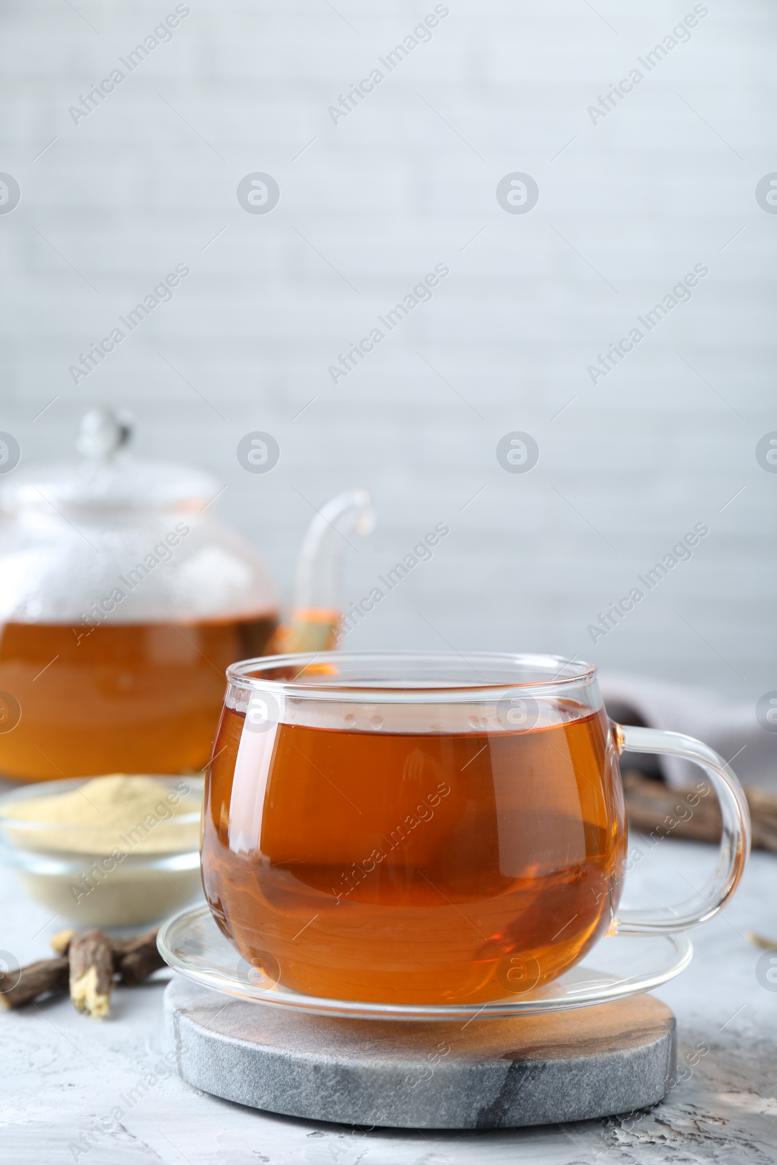 Photo of Aromatic licorice tea on light gray textured table, space for text