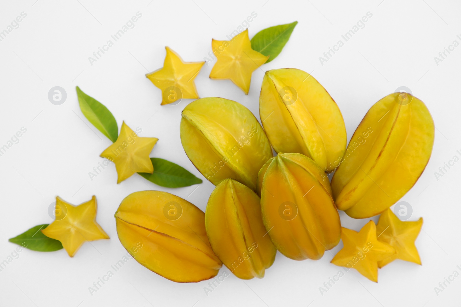 Photo of Delicious cut and whole carambolas, green leaves on white background, top view