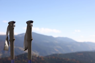 Trekking poles in mountains on sunny day, closeup. Space for text