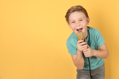 Cute boy singing in microphone on color background. Space for text