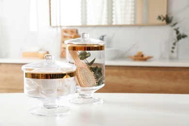 Jars with cotton pads and hairbrush on table in bathroom