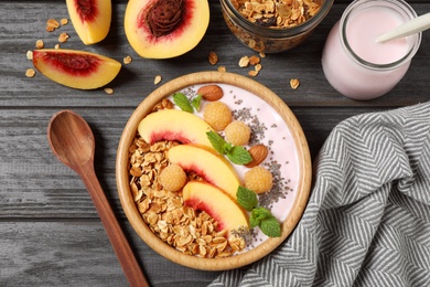 Photo of Tasty homemade granola with yogurt on grey wooden table, flat lay. Healthy breakfast
