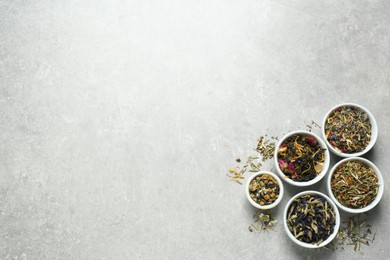 Flat lay composition with different dry teas on light grey table, space for text