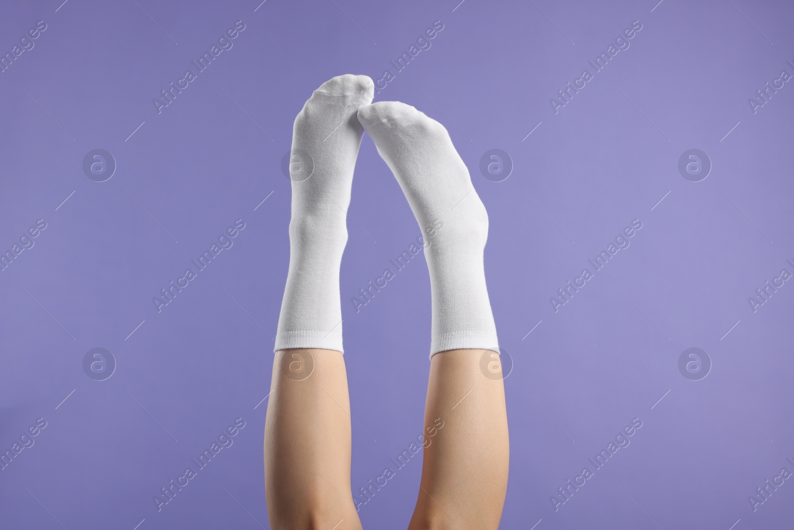 Photo of Woman in stylish white socks on violet background, closeup