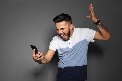 Photo of Portrait of handsome young man with mobile phone on gray background