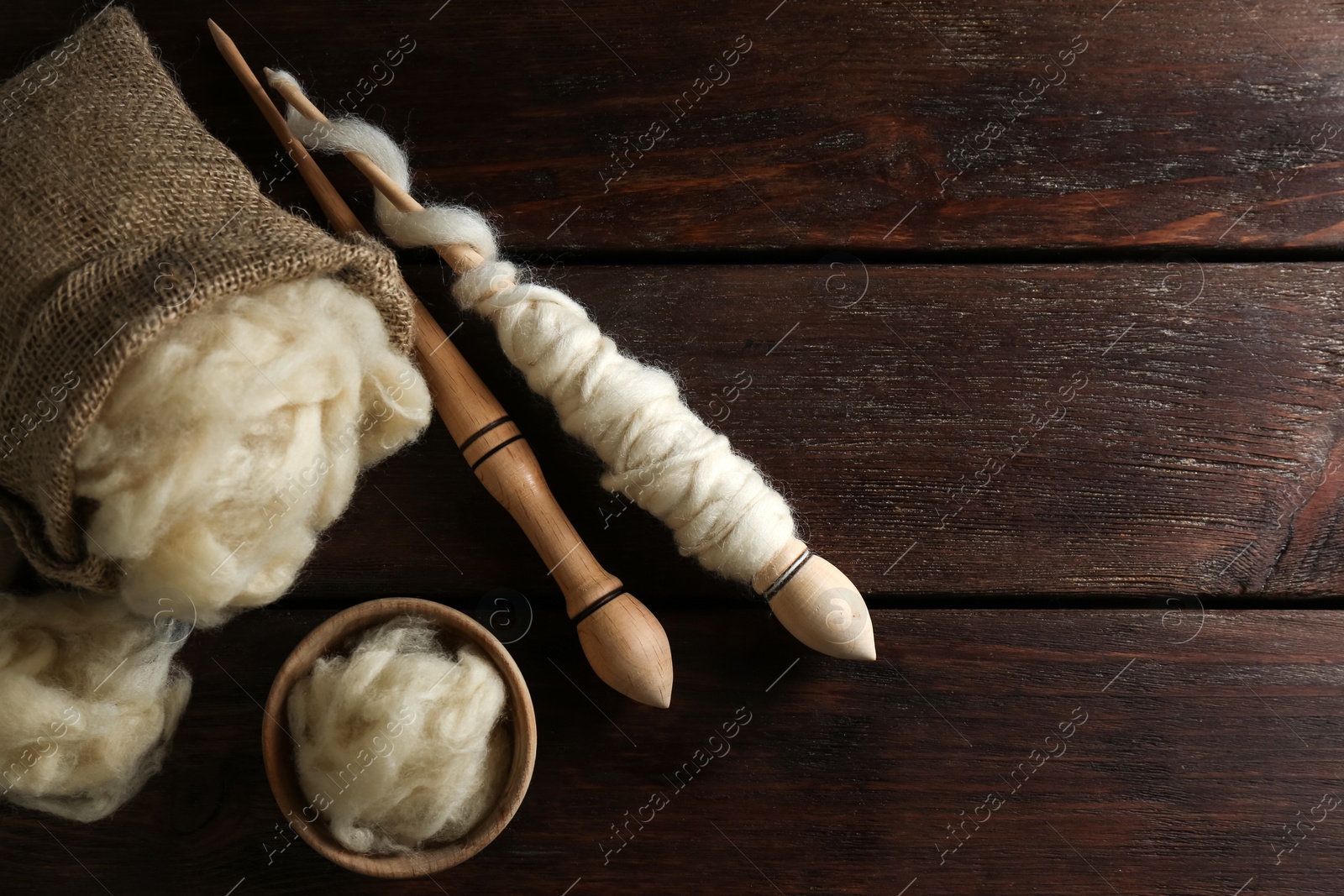 Photo of Soft wool and spindles on white wooden table, flat lay. Space for text