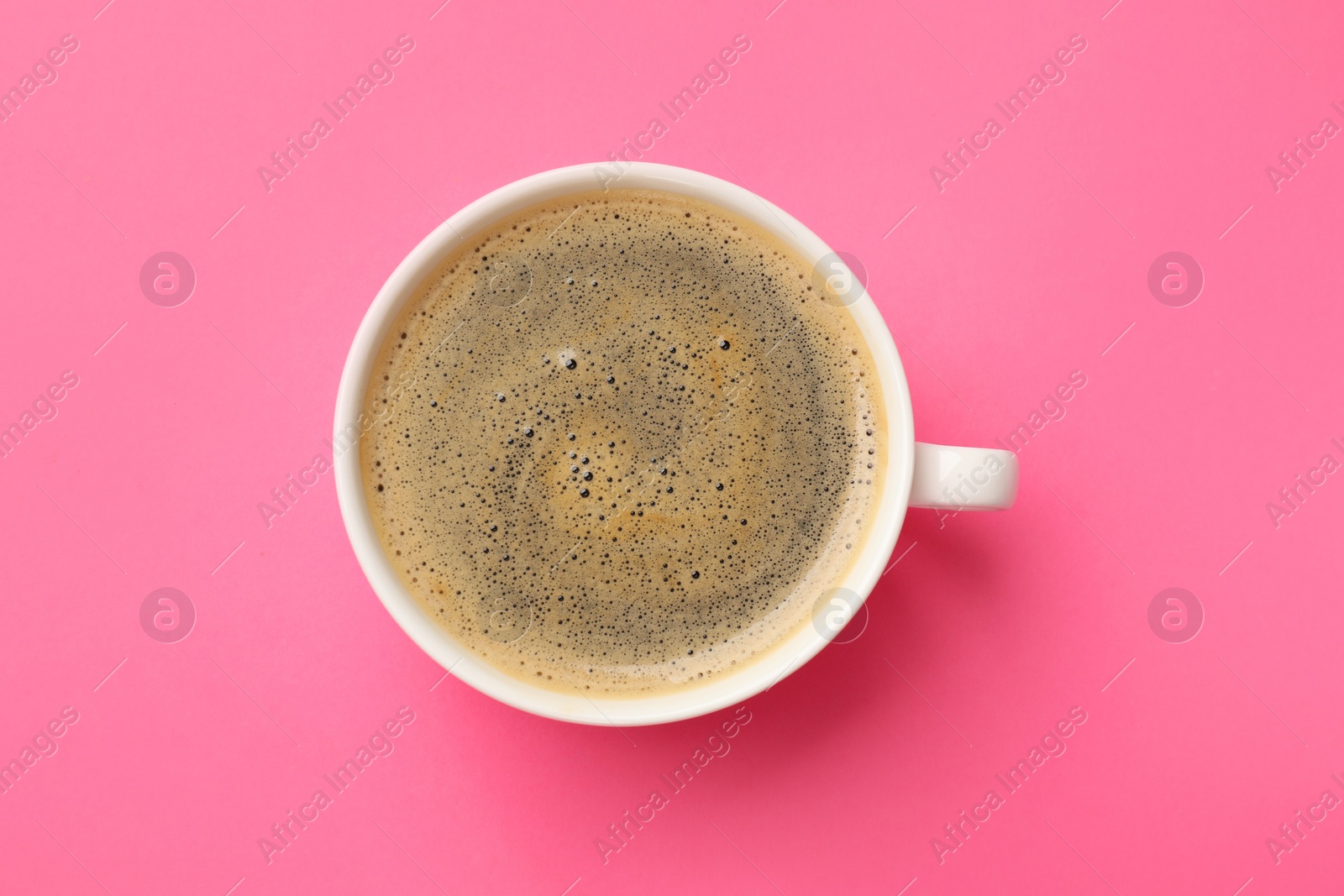 Photo of Fresh coffee in cup on pink background, top view