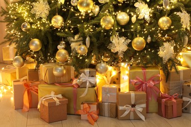 Many gift boxes under decorated Christmas tree at home