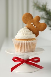 Photo of Tasty Christmas cupcake with cream and gingerbread man cookie on white table