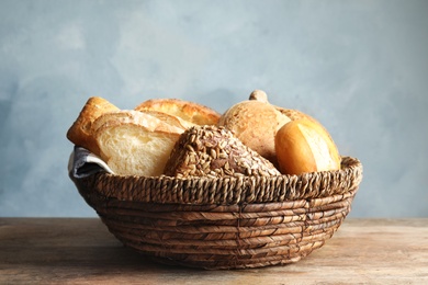 Basket with fresh bread on table against color background