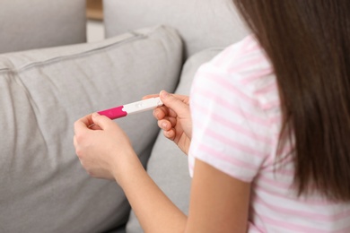 Photo of Young woman with pregnancy test indoors, closeup. Gynecology and childbirth