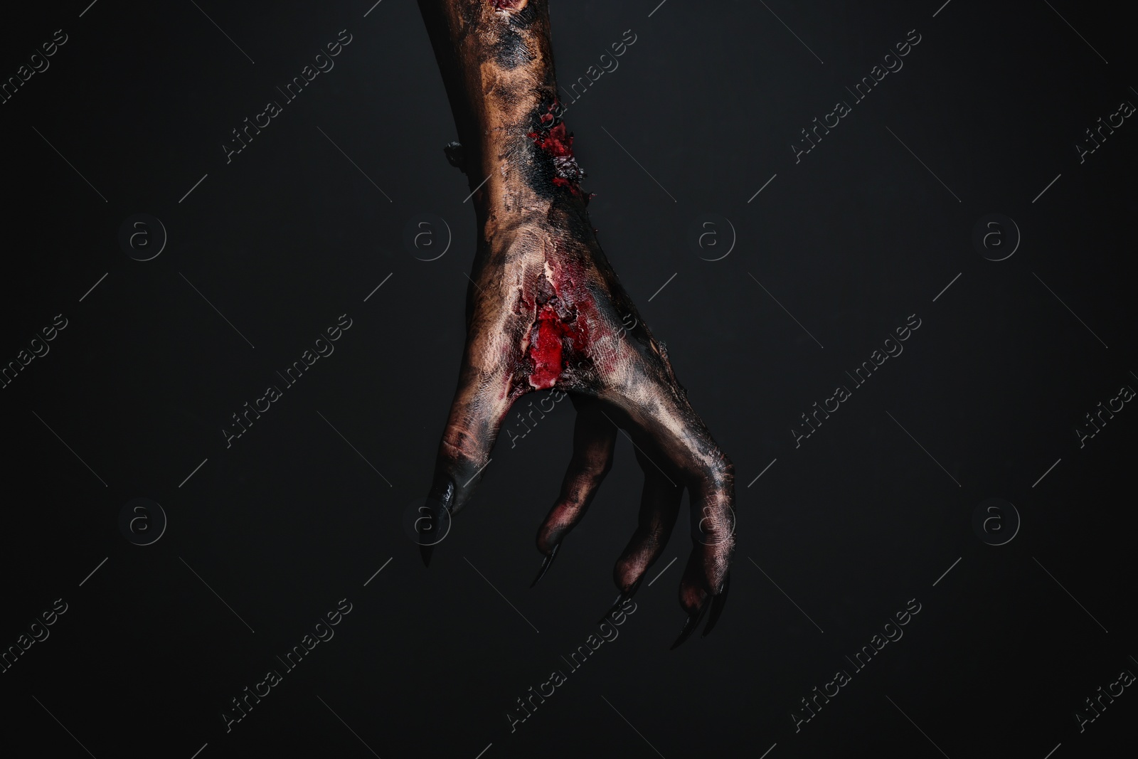 Photo of Scary monster on black background, closeup of hand. Halloween character