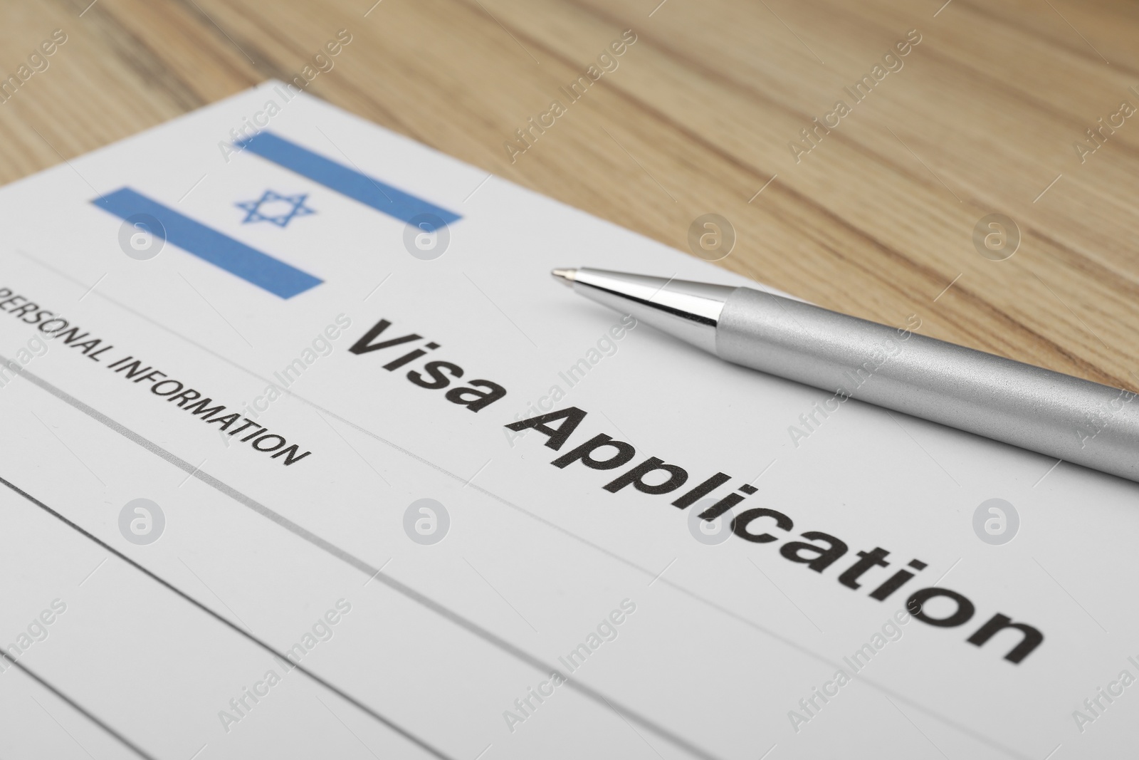 Photo of Immigration to Israel. Visa application form and pen on wooden table, closeup