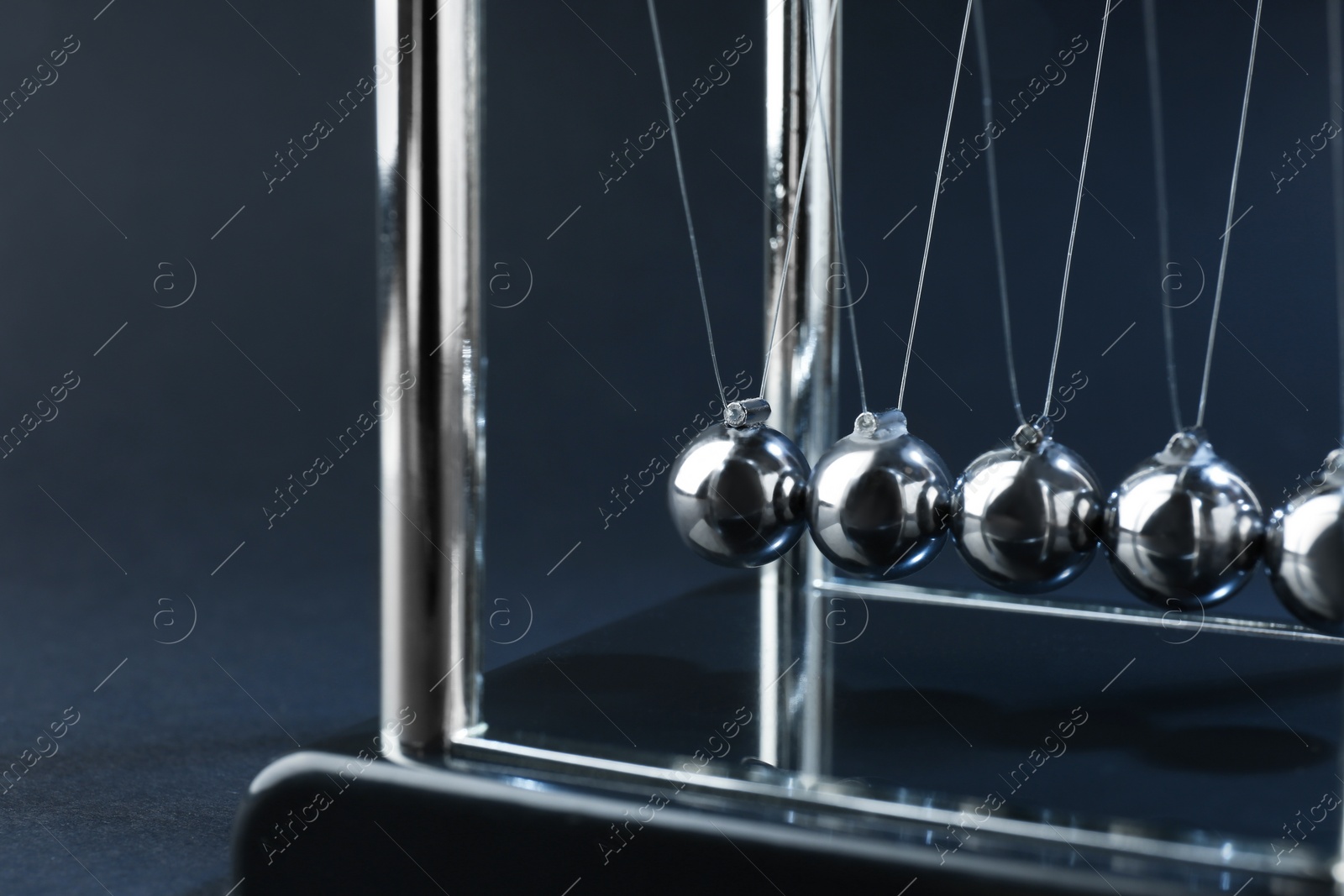 Photo of Newton's cradle on dark background, closeup. Physics law of energy conservation