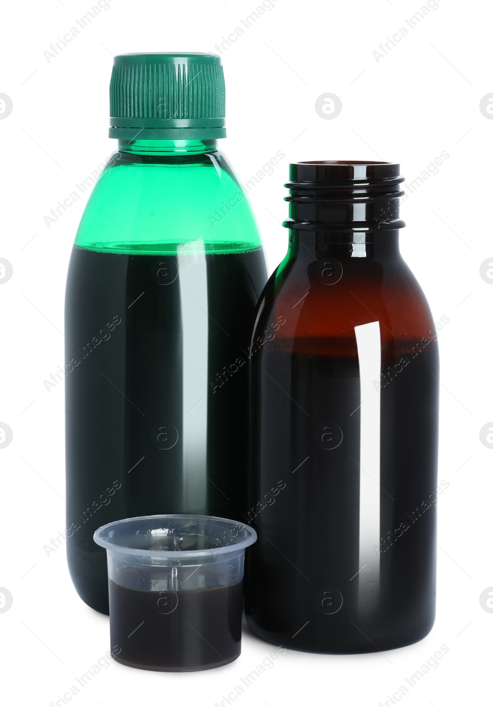 Photo of Bottles of cough syrup and measuring cup on white background
