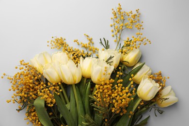 Bouquet with beautiful tulips and mimosa flowers on light grey background, top view