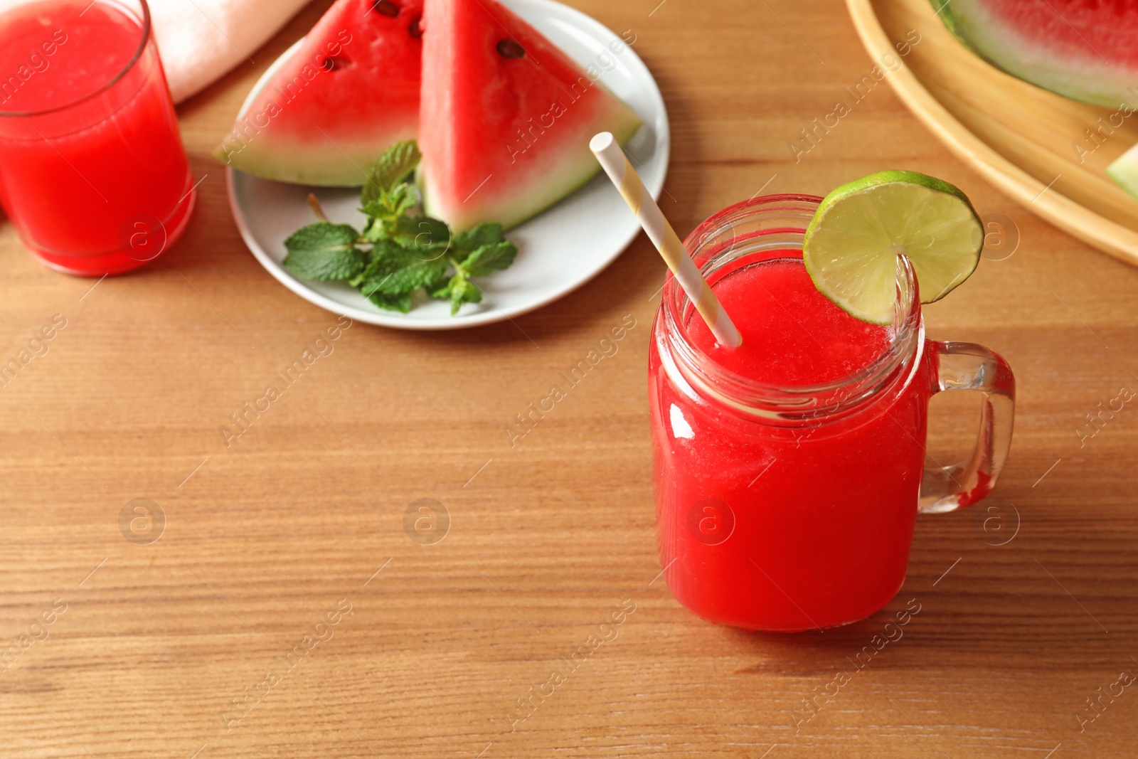 Photo of Summer watermelon drink in mason jar, sliced fruit and space for text on table