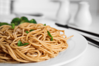 Plate of tasty buckwheat noodles with chopsticks on white table, closeup