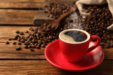Image of Cup of aromatic hot coffee and beans on wooden table. Space for text