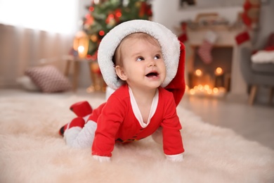 Cute little baby in Christmas costume crawling on fur rug at home