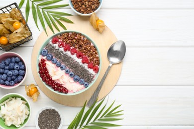 Photo of Tasty smoothie bowl with fresh berries and granola served on white wooden table, flat lay. Space for text