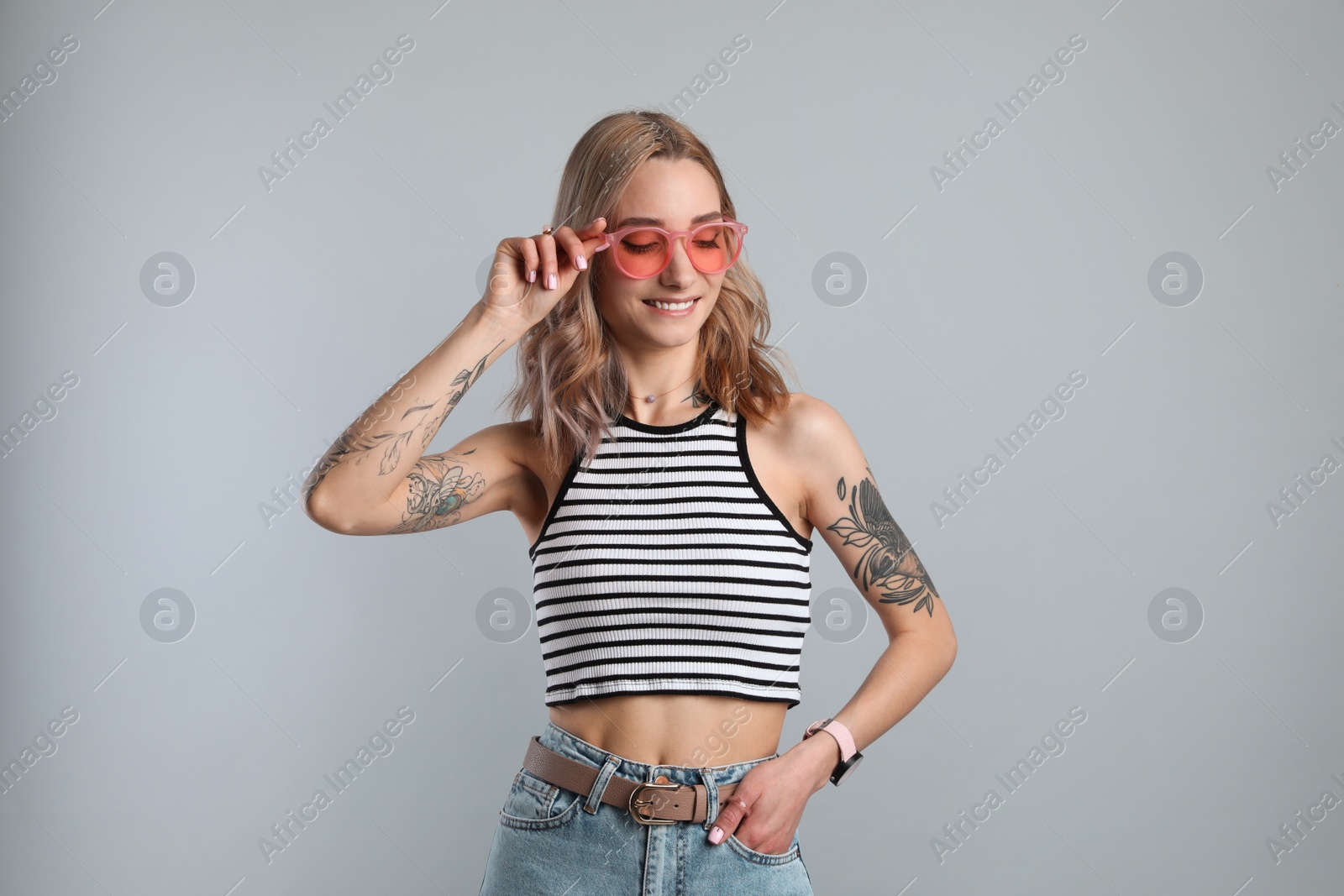 Photo of Beautiful woman with tattoos on body against grey background