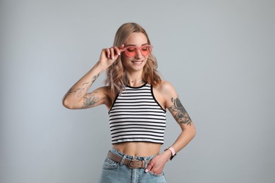 Photo of Beautiful woman with tattoos on body against grey background