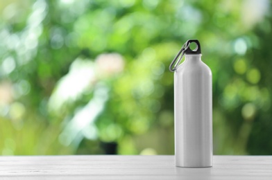 Sports water bottle on table against blurred background. Space for text