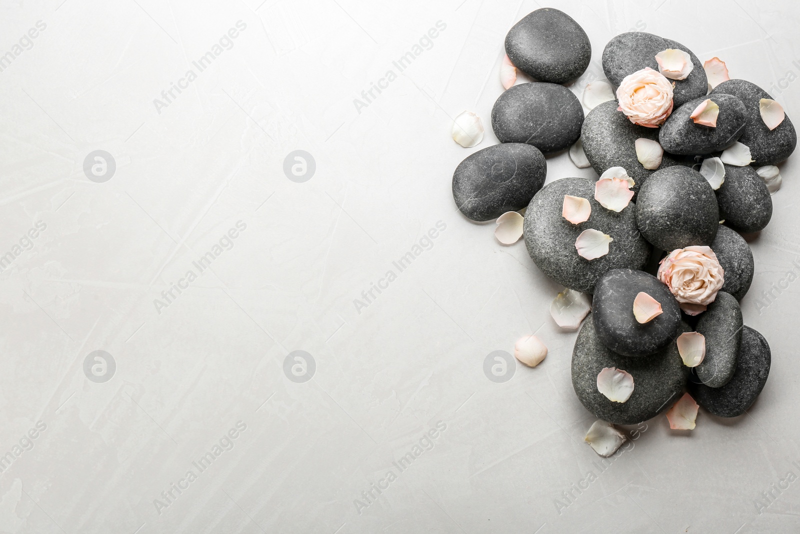 Photo of Stones and flowers on light background, top view with space for text. Zen lifestyle