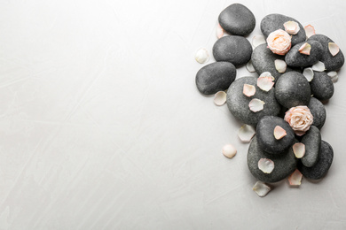 Stones and flowers on light background, top view with space for text. Zen lifestyle