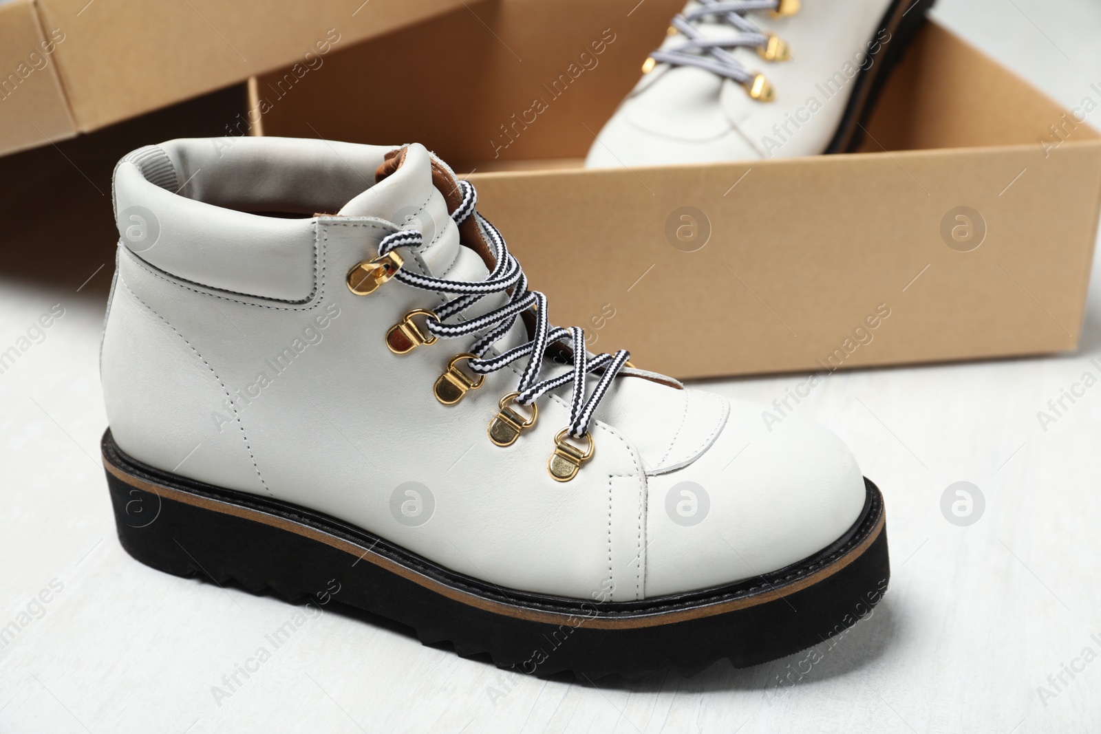 Photo of Pair of stylish boots and box on white wooden background