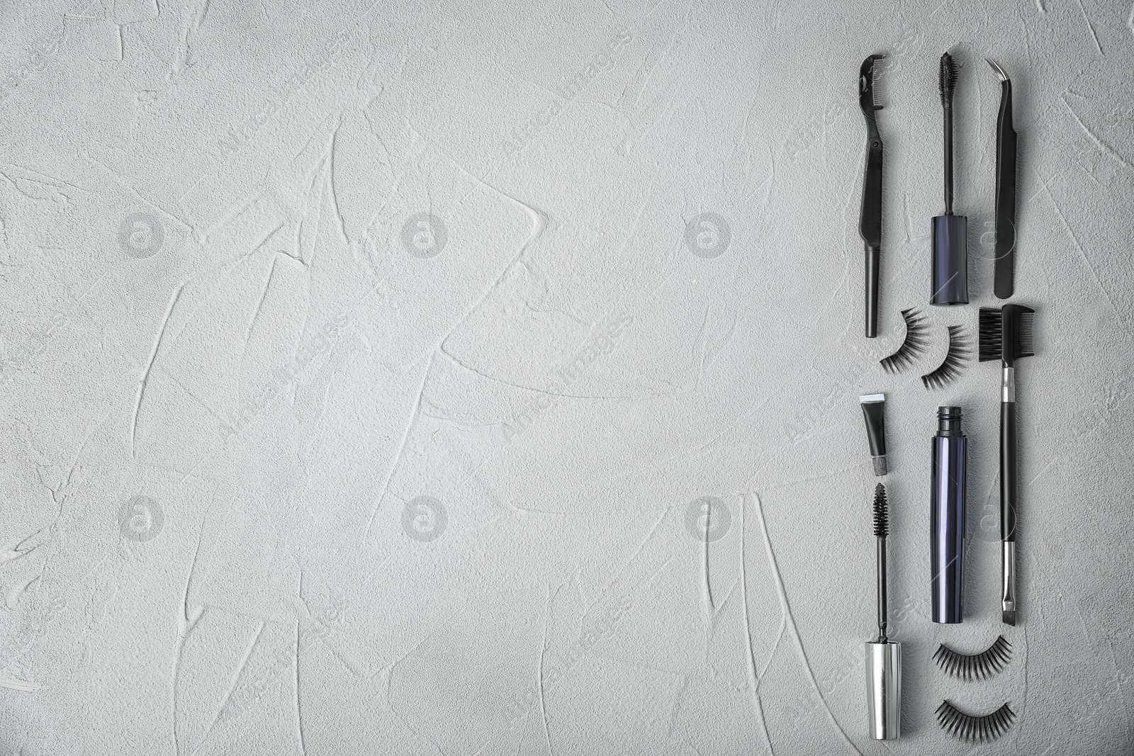 Photo of Flat lay composition with false eyelashes and cosmetic tools on grey background