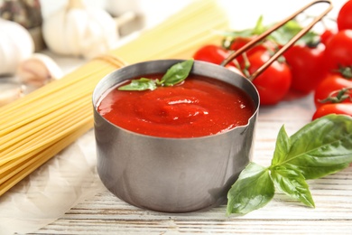 Photo of Pan of tasty tomato sauce served on wooden table