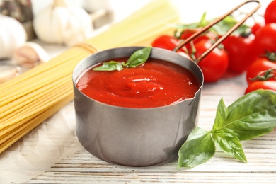 Pan of tasty tomato sauce served on wooden table