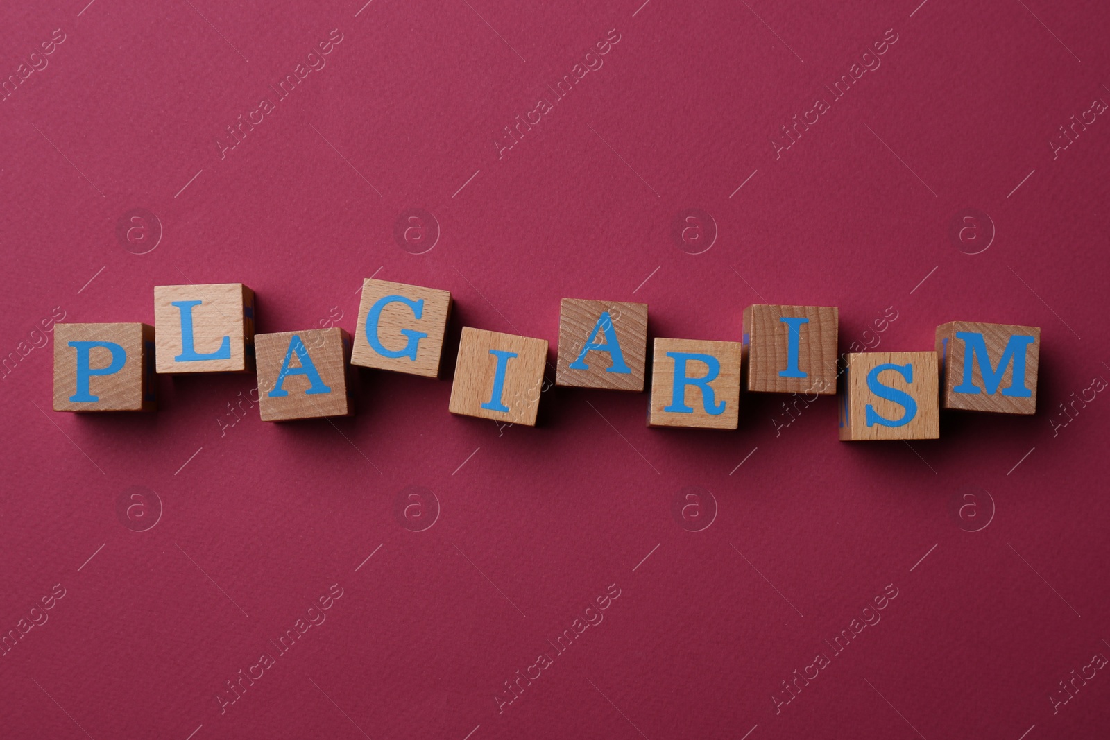 Photo of Wooden cubes with word Plagiarism on dark pink background, flat lay